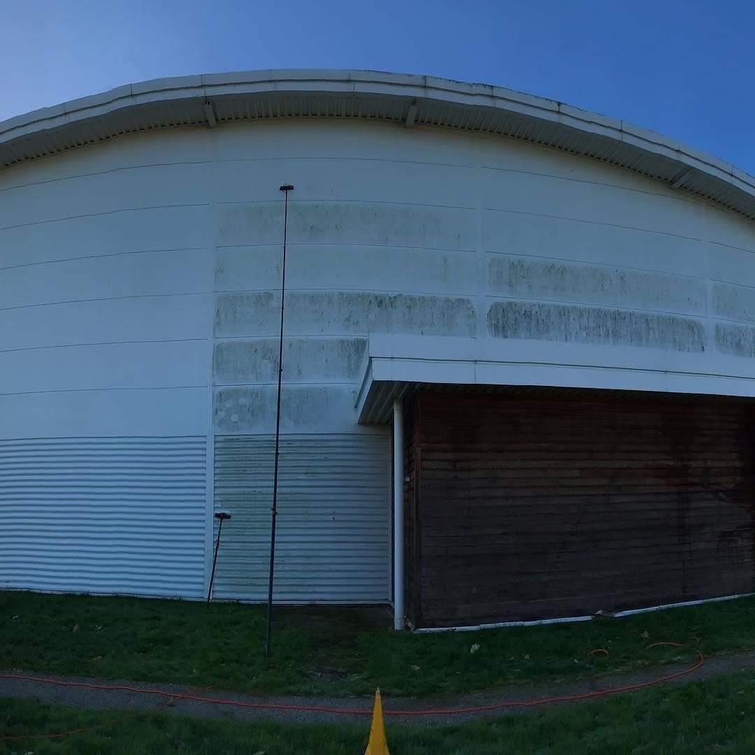 Witte gevelbekleding die met een telescoopstang gereinigd wordt